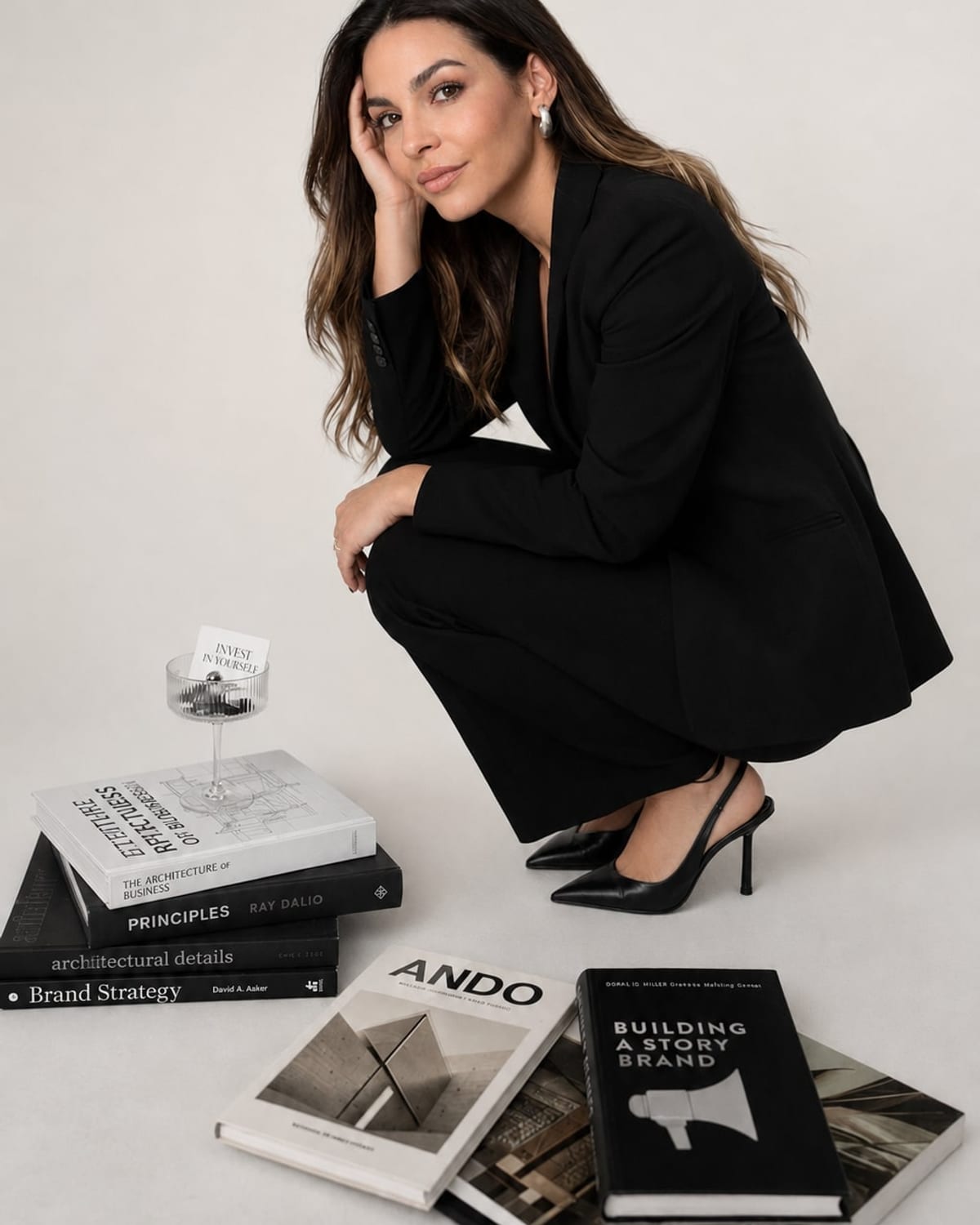 Josefa Taladriz en cuclillas junto a una pila de libros de arquitectura y estrategia de marca
